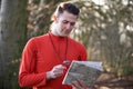 Man Orienteering In Woodlands With Map And Compass