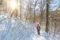 Man in outdoor gear with backpack hiking through snowy forest in the winter