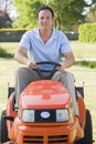 Man outdoors driving lawnmower smiling Royalty Free Stock Photo