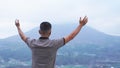 Man with outstretched arms. Person standing alone from behind with raised hands, open arms against the blue morning mountain view Royalty Free Stock Photo