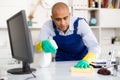 Man in an overalls cleans the table Royalty Free Stock Photo