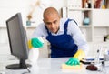 Man in an overalls cleans the table Royalty Free Stock Photo