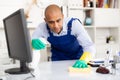 Man in an overalls cleans the table Royalty Free Stock Photo