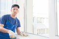 A man in overalls measures the window sill using a tape measure Royalty Free Stock Photo