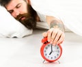 Man overslept, try to turn off alarm clock, white background. Royalty Free Stock Photo