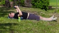 Man with overweight do exercises with dumbbells at outddor in summer