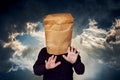 Man with a package on his head on a stormy sky background. The man is looking for a blind road