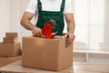 Man packing box with adhesive tape indoors. Moving service