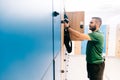 Man packing his gym bag into a blue locker