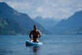 Man on paddle board in Alps lake mountains. Leisure activities with paddle on Lake in Switzerland. Man paddle surfing Royalty Free Stock Photo