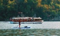 Man on paddle board by the electric tourist boat on Lake Bohinj in Triglav national park