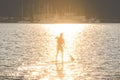 A man on paddle boarding on lake with yachts in background on sunset Royalty Free Stock Photo