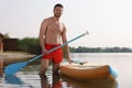 Man with paddle standing near SUP board in water Royalty Free Stock Photo