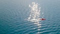 Man paddling single red kayak on blue lake sunny day Royalty Free Stock Photo