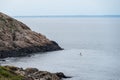 Man paddling on surf board along a rocky dramatic coast of Kullaberg, Sweden