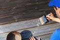 Man restores wooden patio deck with wood protective paint