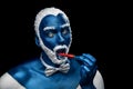 Man painted in blue color with snowy hair and beard eating chili pepper Royalty Free Stock Photo