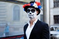 A man with a painted face of a skeleton, a dead zombie, in the city during the day. day of all souls, day of the dead, halloween,