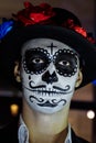 A man with a painted face of a skeleton, a dead zombie, in the city during the day. day of all souls, day of the dead, halloween,