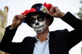 A man with a painted face of a skeleton, a dead zombie, in the city during the day. day of all souls, day of the dead, halloween,