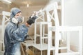 Man painting chair into white paint in respiratory mask. Application of flame retardant ensuring fire protection