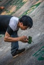 Man painting chinese calligraphy characters on a rock