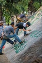 Man painting chinese calligraphy characters on a rock