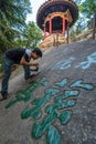 Man painting chinese calligraphy characters on a rock