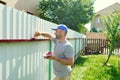Man painting fence. Repair background. Summer outdoor activity. Recolor surface.