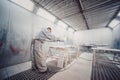 Man painting furniture details. Worker using spray gun.