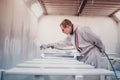 Man painting furniture details. Worker using spray gun.