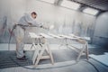 Man painting furniture details. Worker using spray gun.