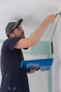 man painting a house wall with a paint Roller. Royalty Free Stock Photo