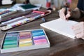 Man painting with pencil and pastel crayon chalks on paper. box of pastel chalks and color pencils on the wooden table Royalty Free Stock Photo