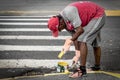 Man painting the sidewalk with a paint brush.