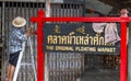 Man painting sign `The original floating market`at Damnoen Saduak floating market in Thailand