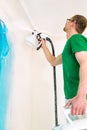 Man painting walls using spray gun