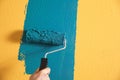 Man painting yellow wall with blue dye, closeup
