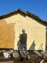 A man paints his house beige with a spray gun. worker spraying paint over timber wood. Construction worker with spray gun Royalty Free Stock Photo