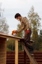 Man paints wooden shelter with spray gun