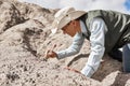 Man paleontologist cleans the find with a brush in the desert