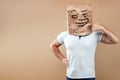 A man with a paper bag on his head, on which an evil face is painted, pretends to be on the phone. Isolated on yellow background, Royalty Free Stock Photo