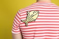 Man with paper fish sticker on against yellow background, closeup. April fool`s day Royalty Free Stock Photo