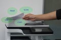 Man with paper on multi functional printer to print, scan, copy and fax in office