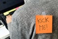 Man with a paper with the text kick me attached to his back Royalty Free Stock Photo