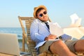 Busy man with papers talking by mobile phone on beach. Business trip Royalty Free Stock Photo