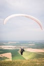 A man paraglider taking off from the edge of the mountain with fields in the background. Paragliding sports Royalty Free Stock Photo