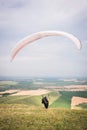 A man paraglider taking off from the edge of the mountain with fields in the background. Paragliding sports Royalty Free Stock Photo