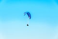 Man paragliding with blue parachute above water sea, clear sky Royalty Free Stock Photo