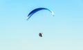 Man paragliding with blue parachute above water sea, clear sky Royalty Free Stock Photo